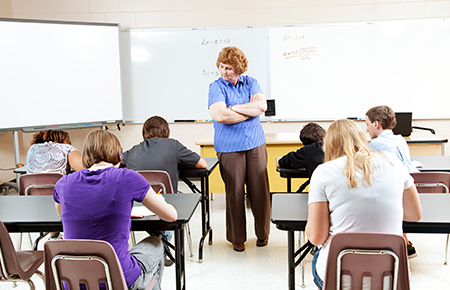 Students giving exam under examiner's supervision